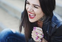 Portrait of young woman laughing, tattoos on neck and hand — Stock Photo