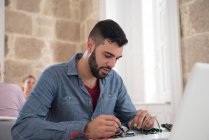 Jeune technicien en informatique mâle réparer le câble sur le bureau — Photo de stock
