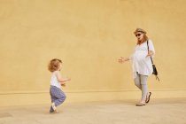 Schwangere Frau und Tochter spielen an gelber Wand — Stockfoto