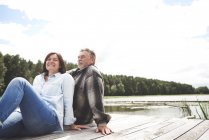 Mature couple relaxing on pier beside lake — Stock Photo