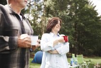 Pareja adulta sosteniendo tazas de té en un entorno rural - foto de stock