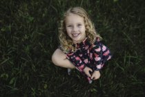 Overhead portrait of blond haired girl sitting on grass — Stock Photo