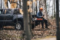 Holzfäller sitzt auf Pick-up-Truck und hält Schutzhandschuhe — Stockfoto