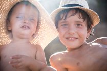Retrato de menino e irmão mais novo na praia usando chapéus de sol, Begur, Catalunha, Espanha — Fotografia de Stock