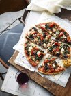 Aufgeschnittener Spinat, Feta und Olivenpizza auf Servierbrett, erhöhte Aussicht — Stockfoto