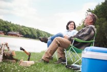 Mature couple sitting in camping chairs beside lake — Stock Photo