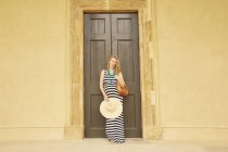 Беременная женщина позирует перед большими двойными дверями — стоковое фото