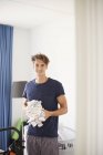 Portrait of man in nursery holding stack of baby clothes — Stock Photo