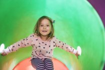 Girl in tube on climbing frame looking at camera — Stock Photo