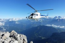 Helicopter approaching at mountain cliff edge — Stock Photo