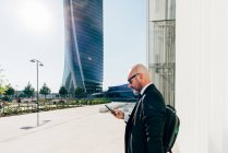 Зрілий бізнесмен стоїть на відкритому повітрі, використовуючи смартфон — стокове фото