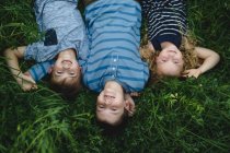 Brothers and sister enjoying outdoors on green grassy field — Stock Photo