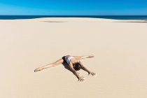 Femme sur la plage de sable en position de yoga — Photo de stock