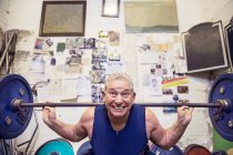 Старший чоловічий пауерліфтер, що піднімає штангу на плечах у спортзалі — стокове фото