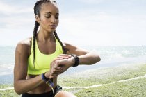 Junge Frau in Sportkleidung schaut auf Activity Tracker — Stockfoto