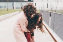 Jovem casal ao ar livre, brincando, jovem abraçando jovem mulher, rindo — Fotografia de Stock