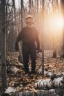Чоловічий лісоруб, що несе бензопилу в сонячному осінньому лісі — стокове фото