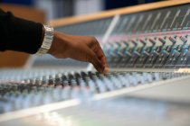 Hand of male college student at sound mixer in recording studio — Stock Photo