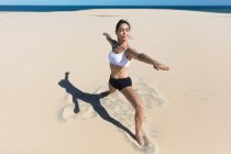 Frau am Strand dehnt sich in Yogaposition — Stockfoto
