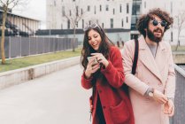 Junges Paar im Freien, junge Frau schaut aufs Smartphone, lacht — Stockfoto
