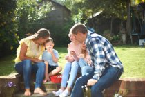 Family, sitting in garden, eating sweets — Stock Photo