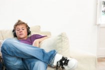 Teenager sitzt auf Sofa und hört Kopfhörermusik — Stockfoto