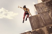 Молодая бегунья прыгает по морской стене — стоковое фото