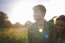 Jovem casal passeando no campo iluminado pelo sol — Fotografia de Stock