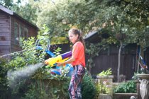 Teenage girl squirting water gun in garden — Stock Photo