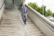 Бізнесмен йде сходами, роблячи телефонний дзвінок на смартфон — стокове фото