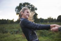 Junge Frau hält Freund an den Händen und dreht sich im Feld — Stockfoto