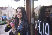 Портрет молодой женщины, которая ест мороженое, татуировки на руке — стоковое фото