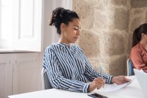 Geschäftsfrau liest Papierkram am Schreibtisch — Stockfoto
