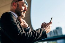 Зрелый бизнесмен использует смартфон на открытом воздухе — стоковое фото
