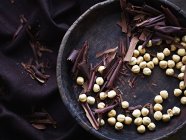 Chocolate shavings and hazelnuts in bowl, overhead view — Stock Photo