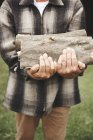 Mature man outdoors holding firewood — Stock Photo