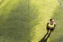 Jeune femme en vêtements de sport debout sur les algues — Photo de stock