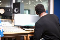 Rear view of young male college student at sound mixer in recording studio — Stock Photo
