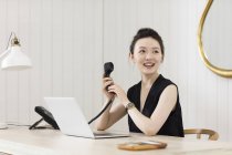 Young woman at desk with telephone handset — Stock Photo