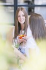 Two young female friends chatting over cocktails at sidewalk cafe — Stock Photo