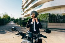 Homem de negócios maduro sentado na motocicleta e colocando no capacete da motocicleta — Fotografia de Stock