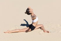 Вид збоку жінки на пляжі робить йогу — стокове фото
