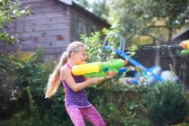 Girl squirting water gun in garden — Stock Photo