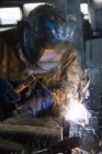 Blacksmith in welding mask welding metal in workshop — Stock Photo