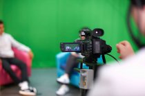 Young male and female college students practicing in TV studio with green screen — Stock Photo