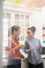 Two businesswomen laughing while taking a coffee break in office kitchen — Stock Photo