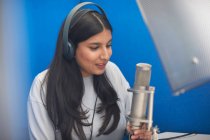 Giovane studentessa universitaria al microfono in studio di registrazione TV — Foto stock