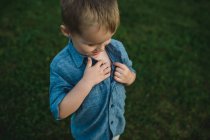 Boy unbuttoning shirt to investigate chest — Stock Photo