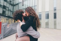 Young couple outdoors, kissing, woman's legs wrapped around man — Stock Photo