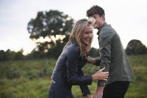 Junges Paar lacht und albert auf Feld herum — Stockfoto